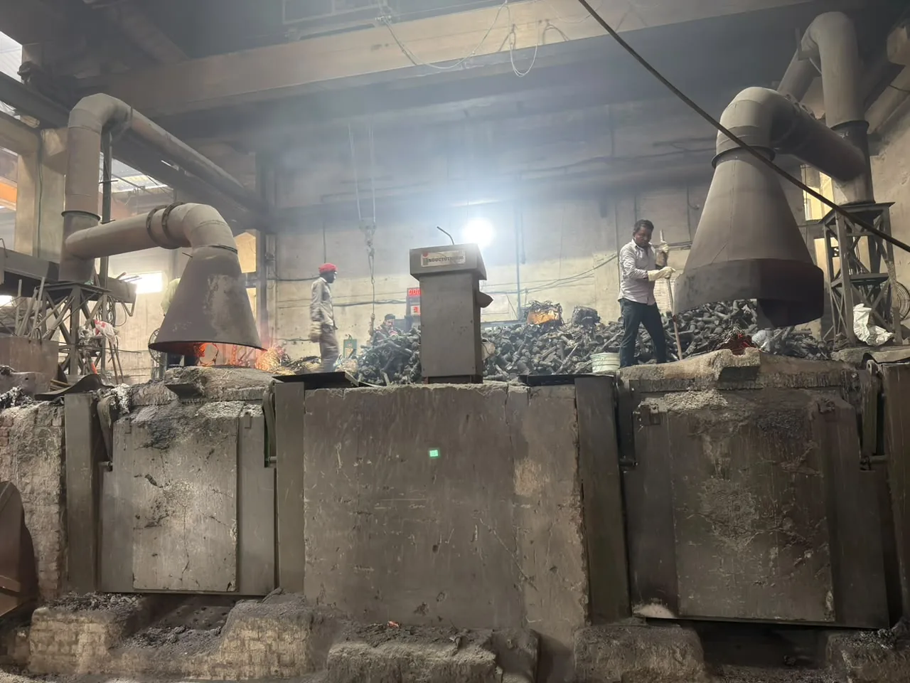 Induction furnaces with extraction hoods on the melt shop floor